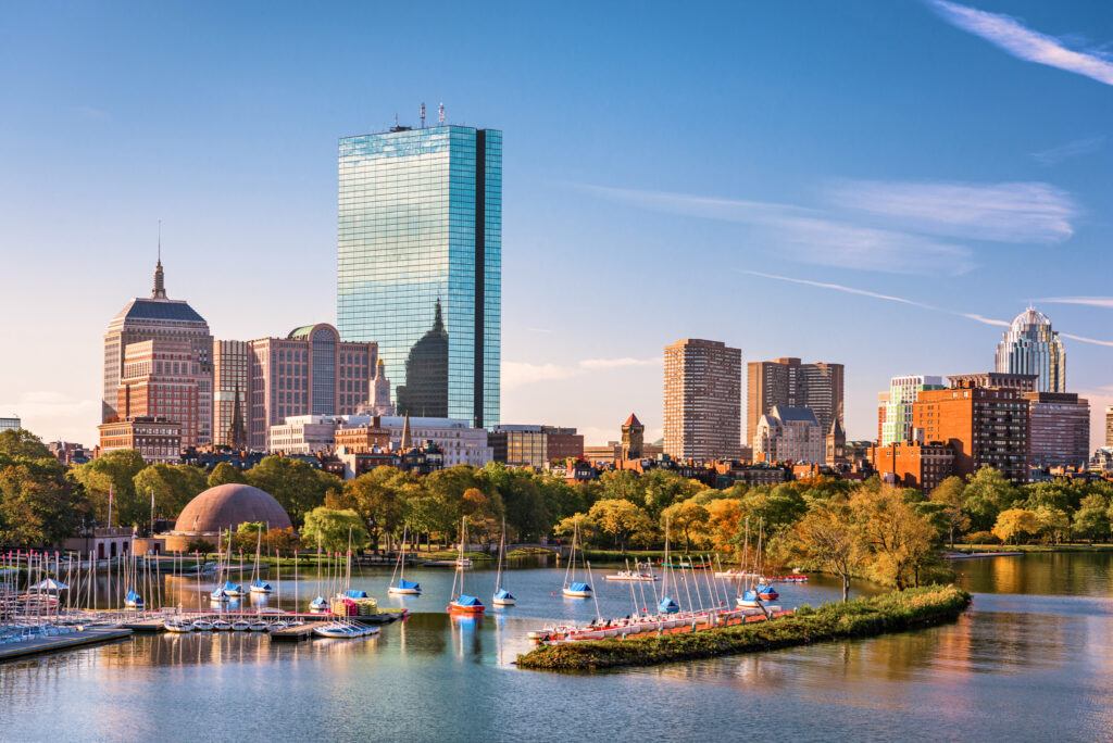 Skyline of Boston with modern and historic buildings reflecting on the waterfront.