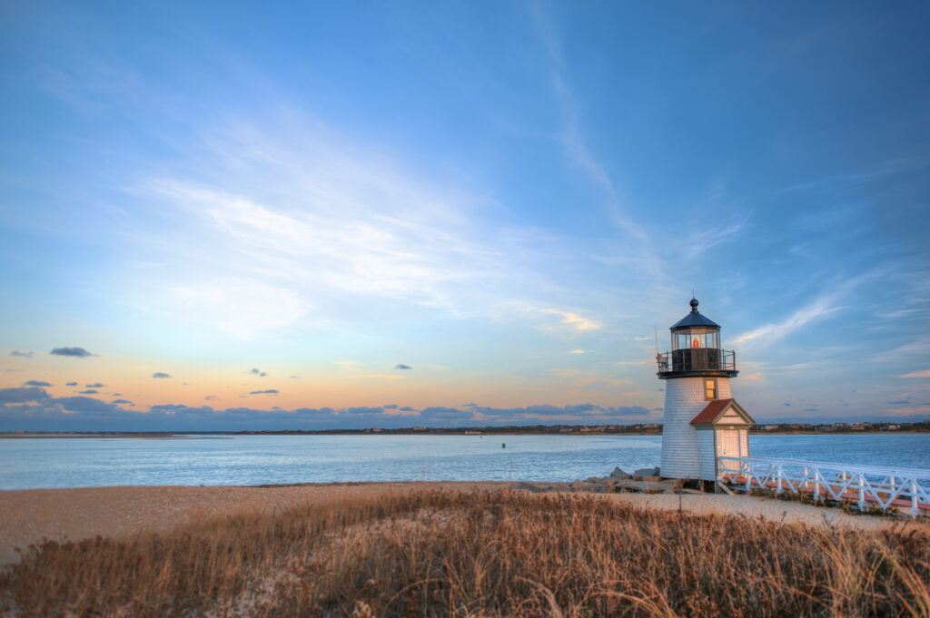 Brant Point Lighthouse in Nantucket, MA, viewed from the shore at dusk with overcast skies and calm waters