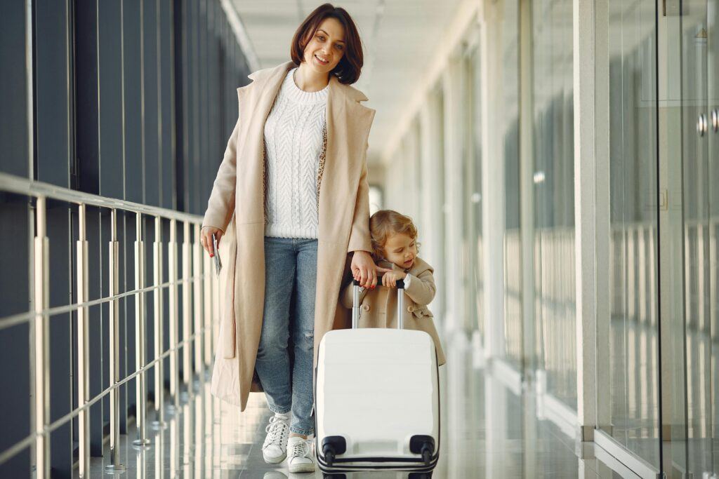 a mom helps her daughter pull a carry-on in the airport 